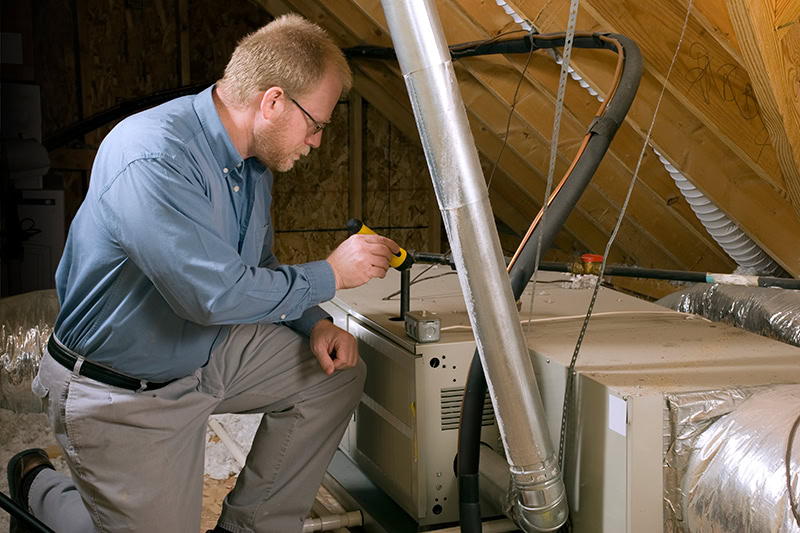 Furnace Maintenance and Winter Energy Saving Tips. A technician working on a unit.